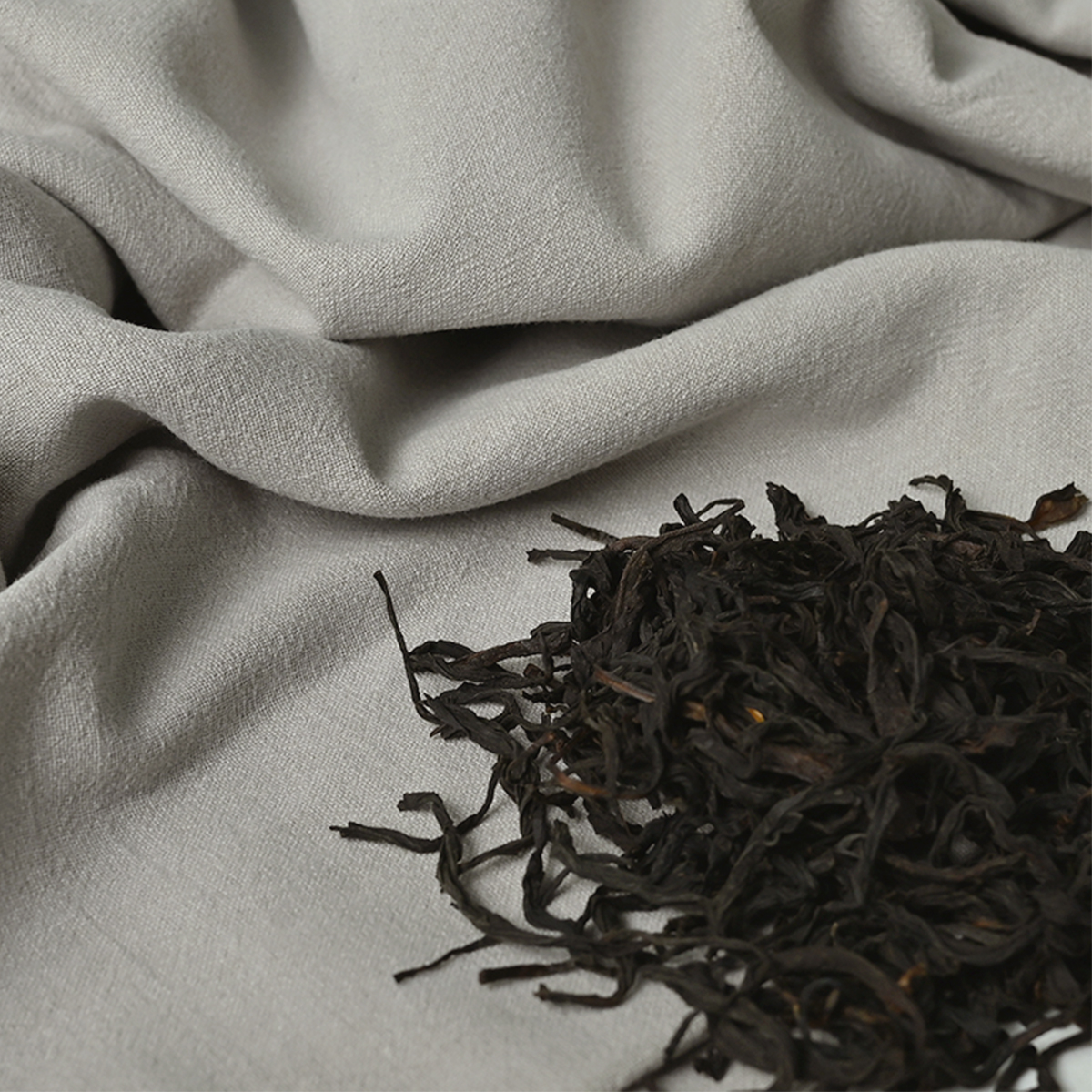 Tea leaves arranged on a naturally colored textile.